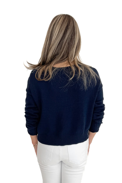 Back view of woman wearing True Navy Paradise Reef Sienna Sweater by Z Supply with jeans against white studio background.