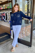Front view of woman wearing True Navy Paradise Reef Sienna Sweater by Z Supply with jeans standing outside of Swagger Boutique.