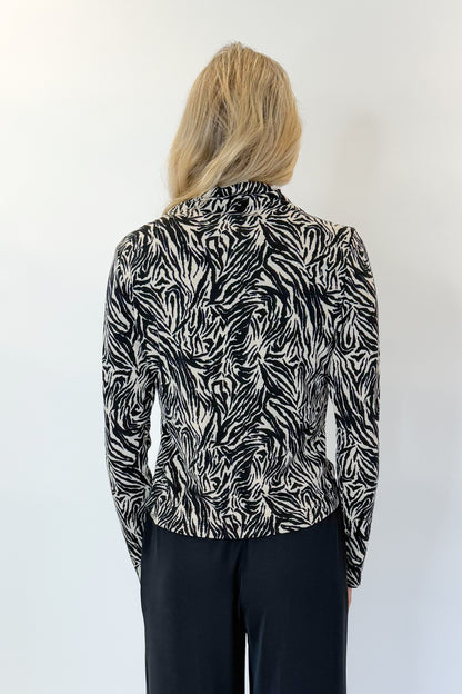 Back view of woman wearing Swagger Boutique’s Black High Waisted Trousers by Skies Are Blue &amp; Zebra Mock Neck Long Sleeve Top by Entro against white studio background.