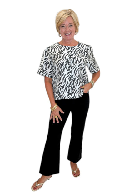 Front view of woman wearing Swagger Boutique’s Zebra Print Button Down Top with jeans against white studio background.