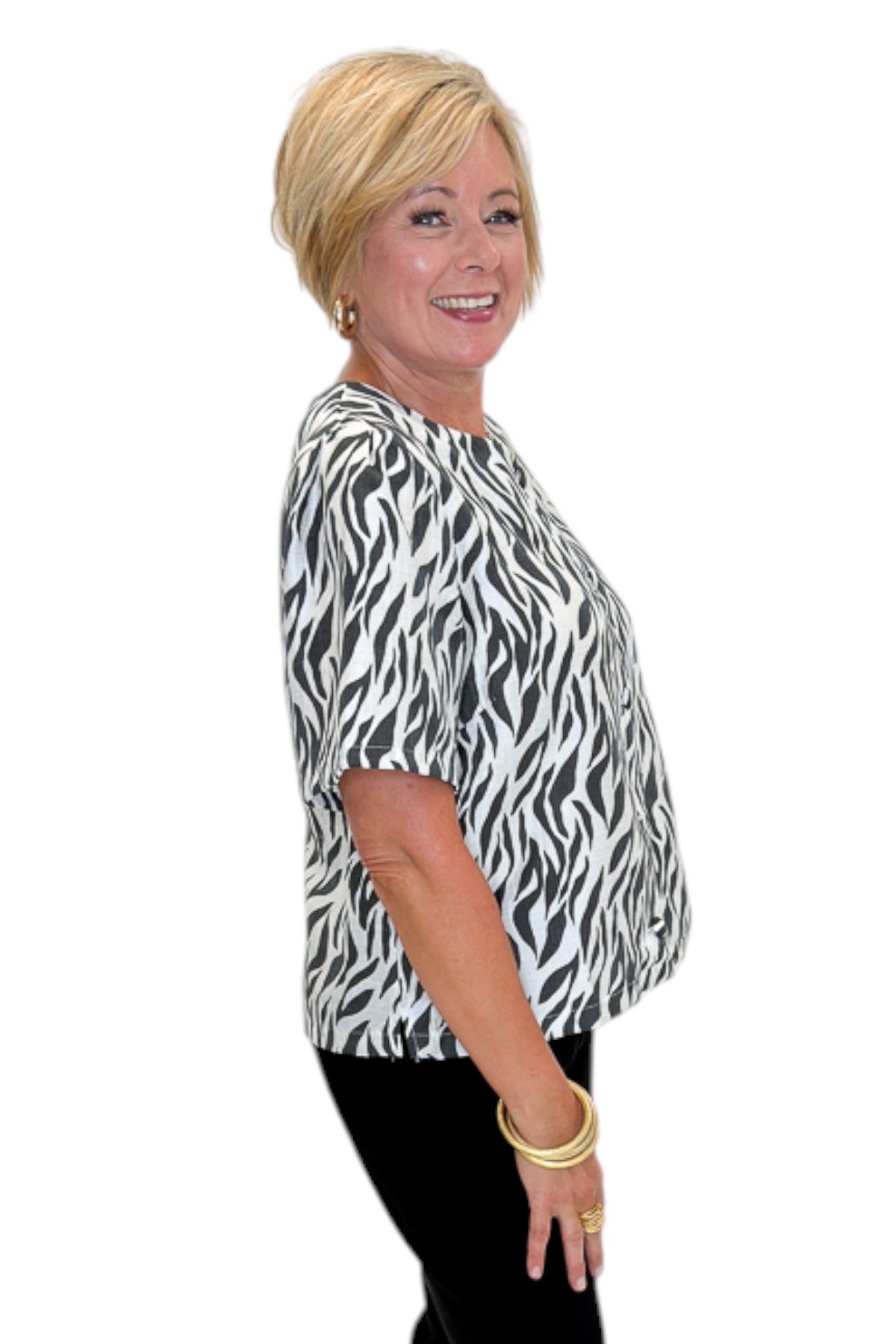 Side view of woman wearing Swagger Boutique’s Zebra Print Button Down Top with jeans against white studio background.