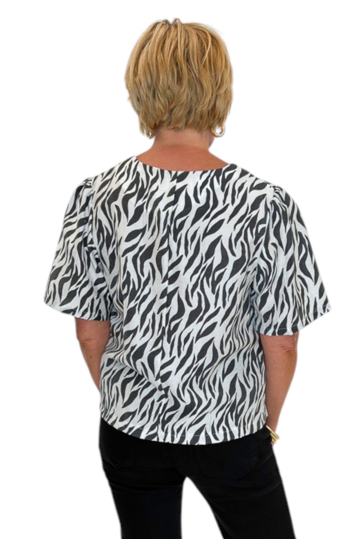 Back view of woman wearing Swagger Boutique’s Zebra Print Button Down Top with jeans against white studio background.