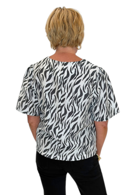 Back view of woman wearing Swagger Boutique’s Zebra Print Button Down Top with jeans against white studio background.