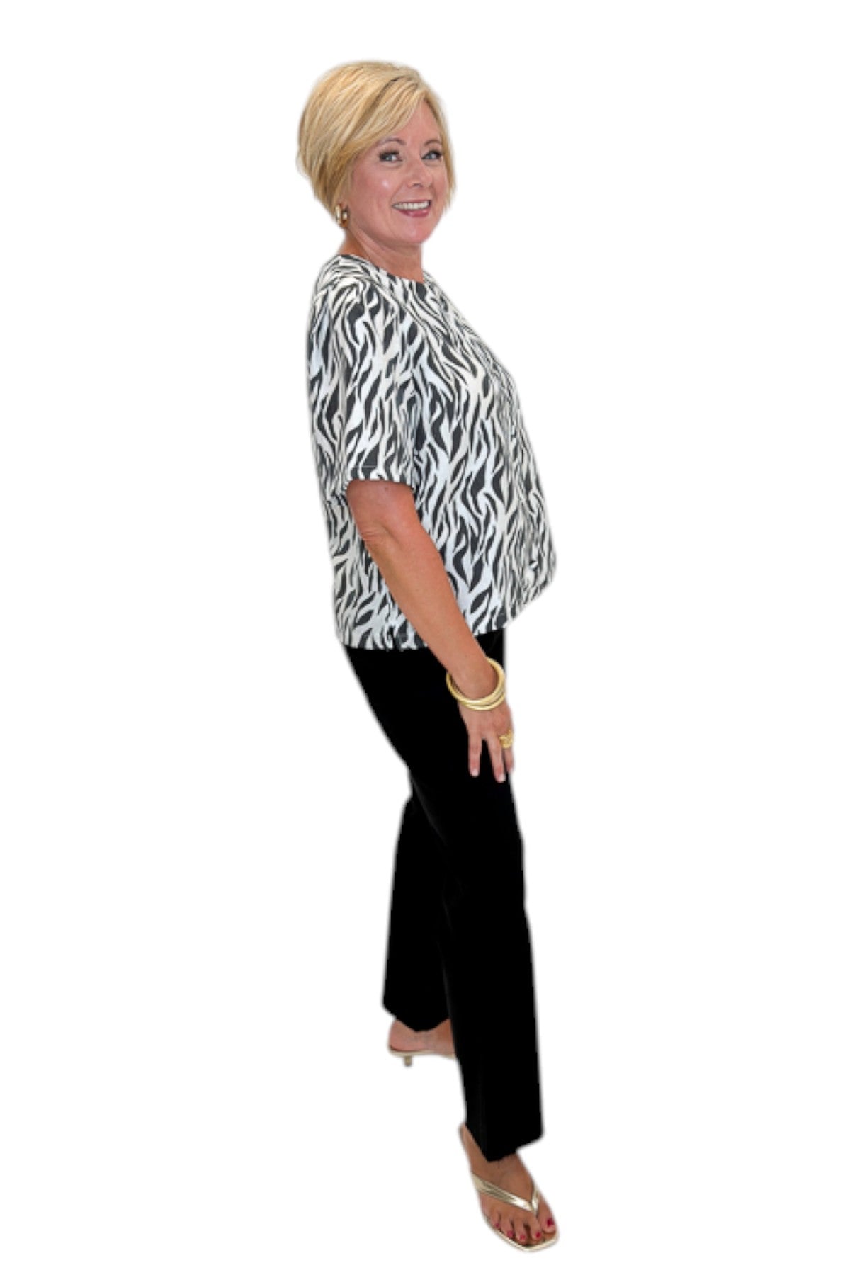 Side view of woman wearing Swagger Boutique’s Zebra Print Button Down Top with jeans against white studio background.