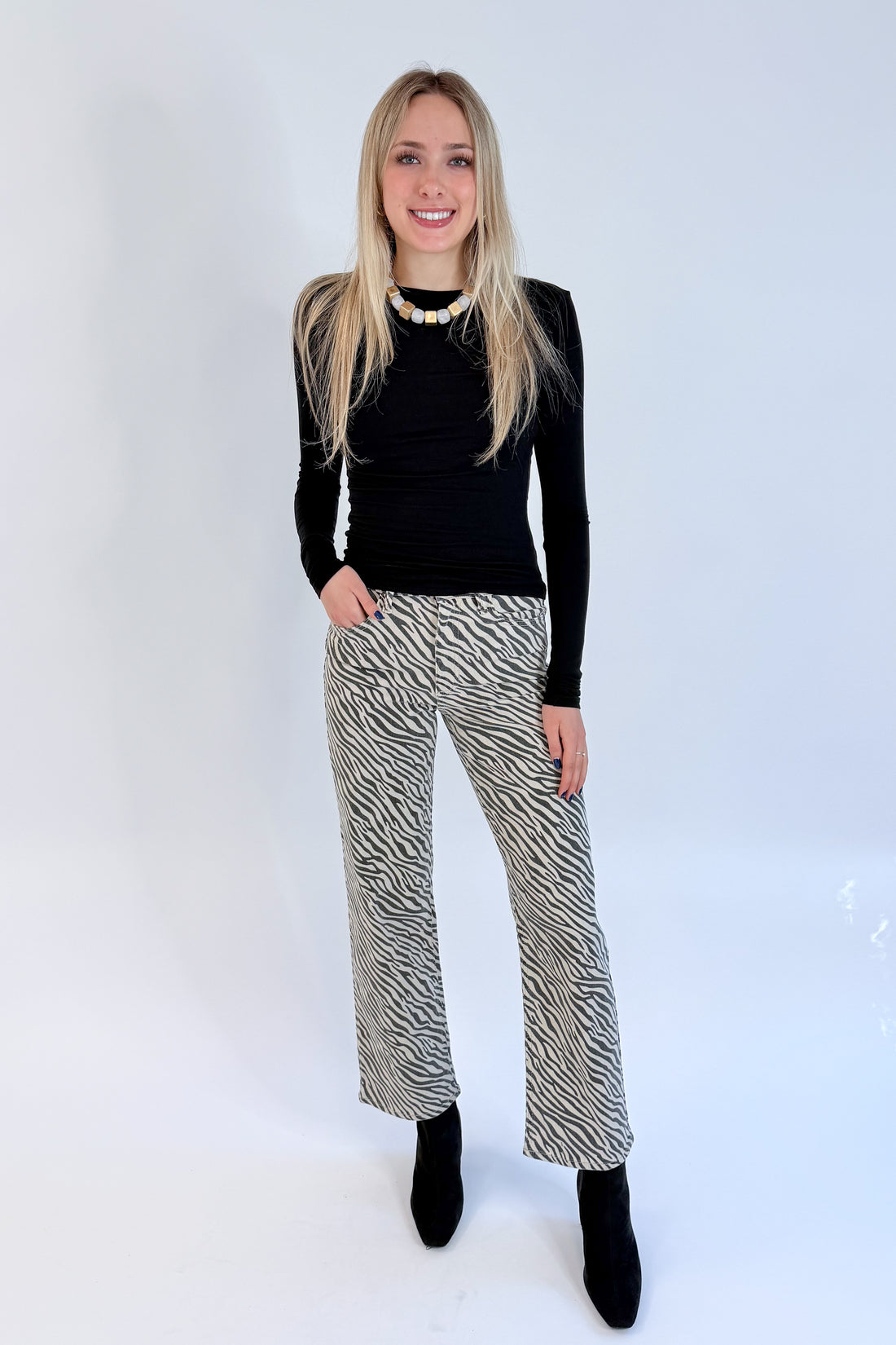 Front view of woman wearing Swagger Boutique’s top with Zebra Straight Leg Jeans by Just Black Denim against white studio background.