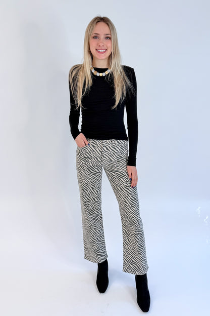Front view of woman wearing Swagger Boutique’s top with Zebra Straight Leg Jeans by Just Black Denim against white studio background.