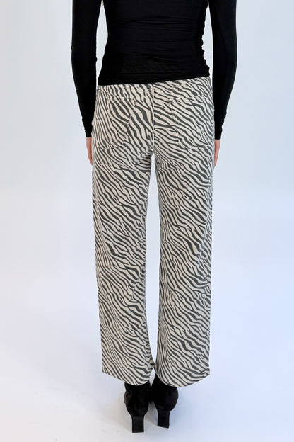 Back detail view of woman wearing Swagger Boutique’s top with Zebra Straight Leg Jeans by Just Black Denim against white studio background.