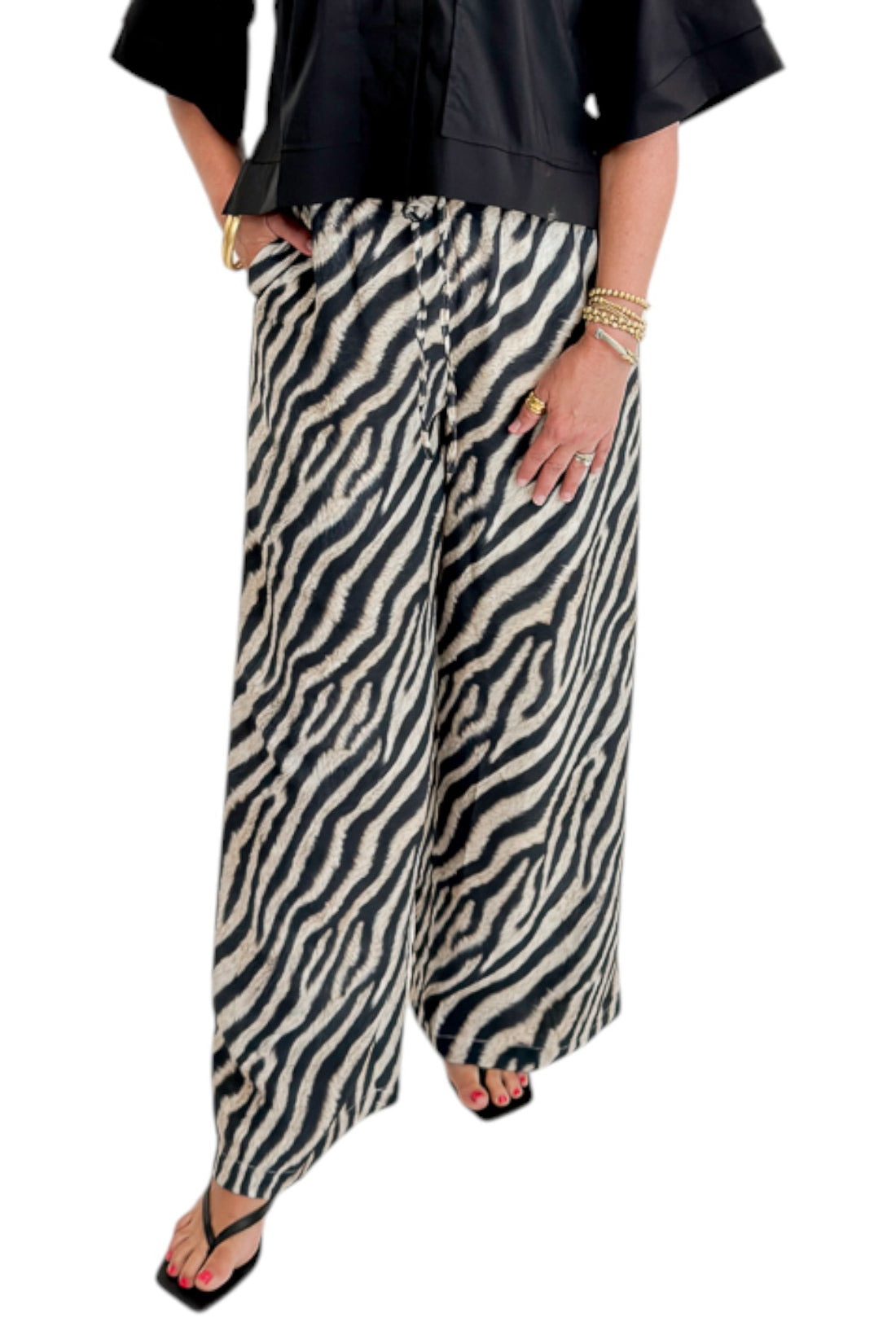 Front view of woman wearing Swagger Boutique’s Black Collared Short Sleeve Top with Zebra Wide Leg Pants by Entro against white studio background.