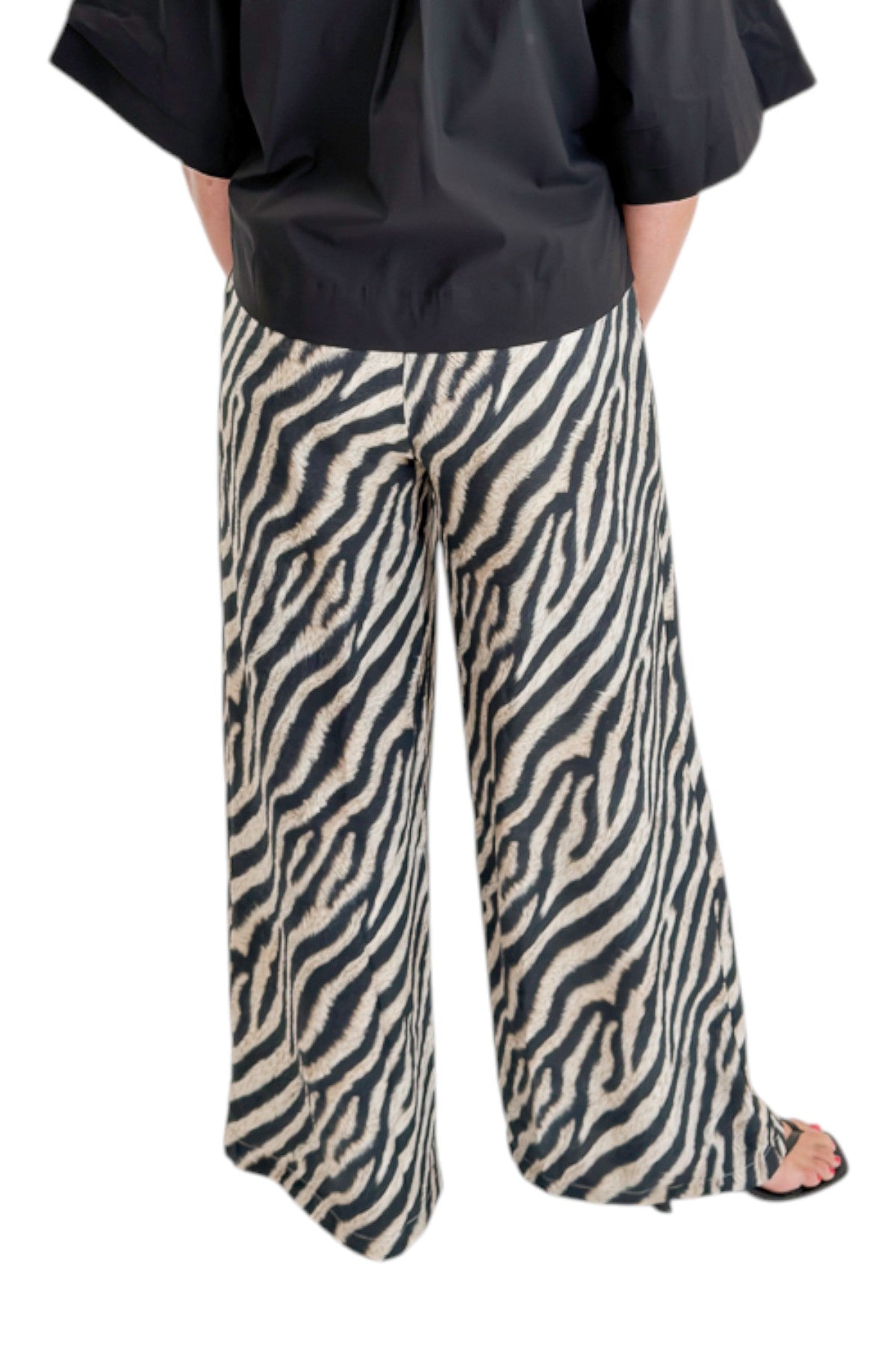 Back view of woman wearing Swagger Boutique’s Black Collared Short Sleeve Top with Zebra Wide Leg Pants by Entro against white studio background.