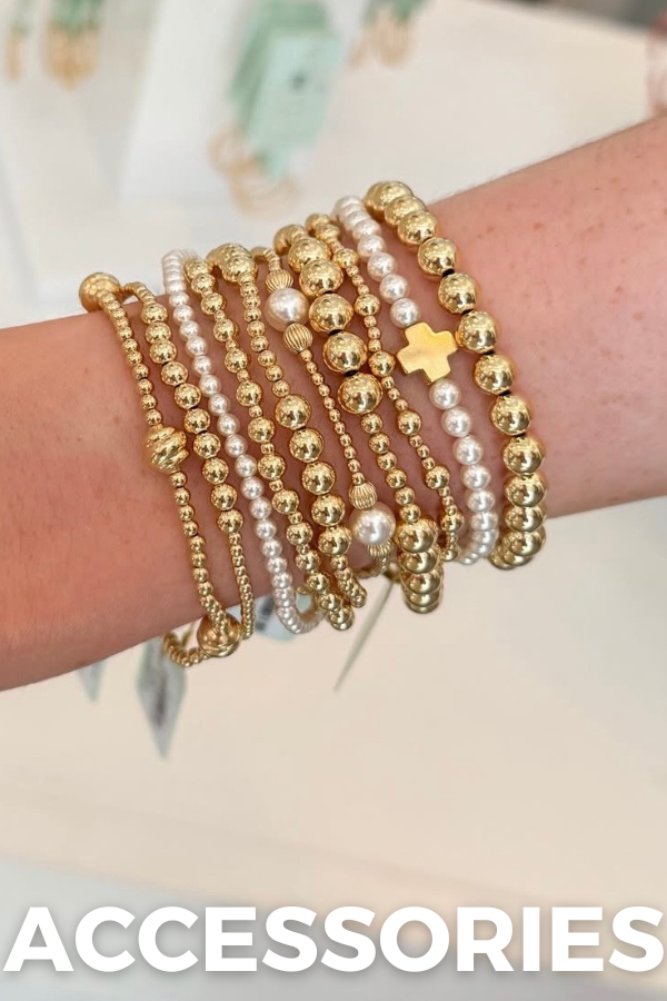 Multiple gold and pearl beaded bracelets on a wrist with a blurred background