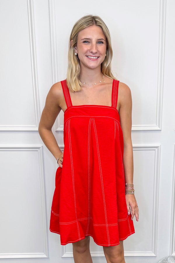 Woman wearing a red dress against a white paneled wall