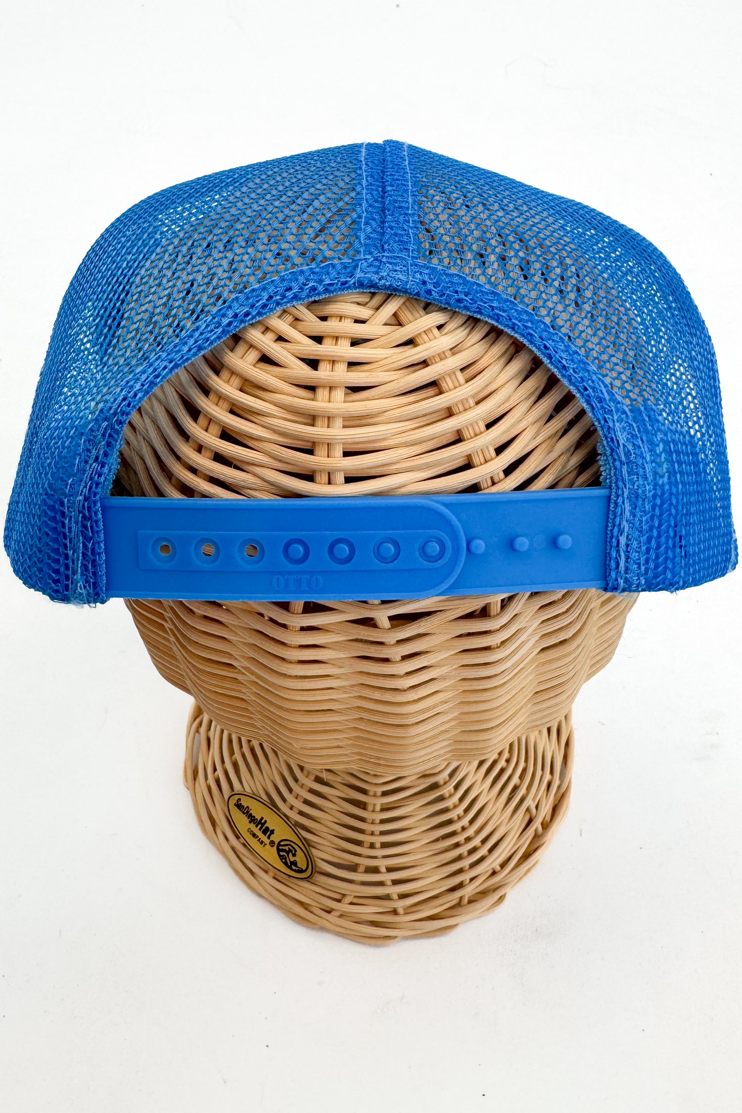 Blue mesh cap on a wicker mannequin head with a visible brand logo.