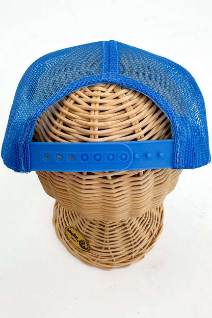 Blue mesh cap on a wicker mannequin head with a visible brand logo.
