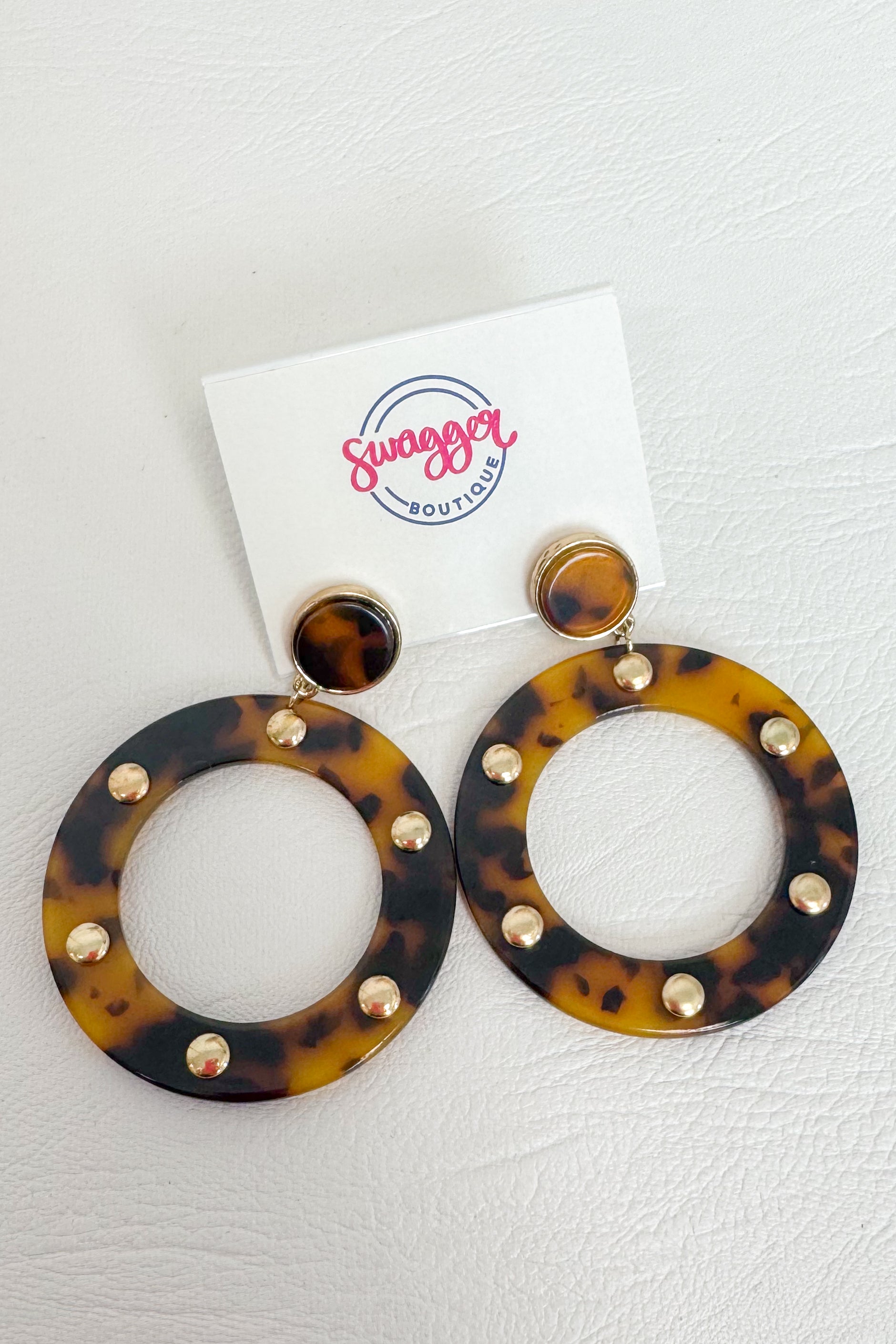 Tortoiseshell hoop earrings with gold-tone studs, displayed on a white card labeled &