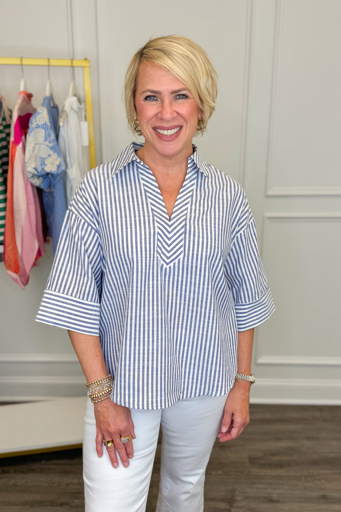 Woman wearing a blue and white striped shirt in a clothing store.