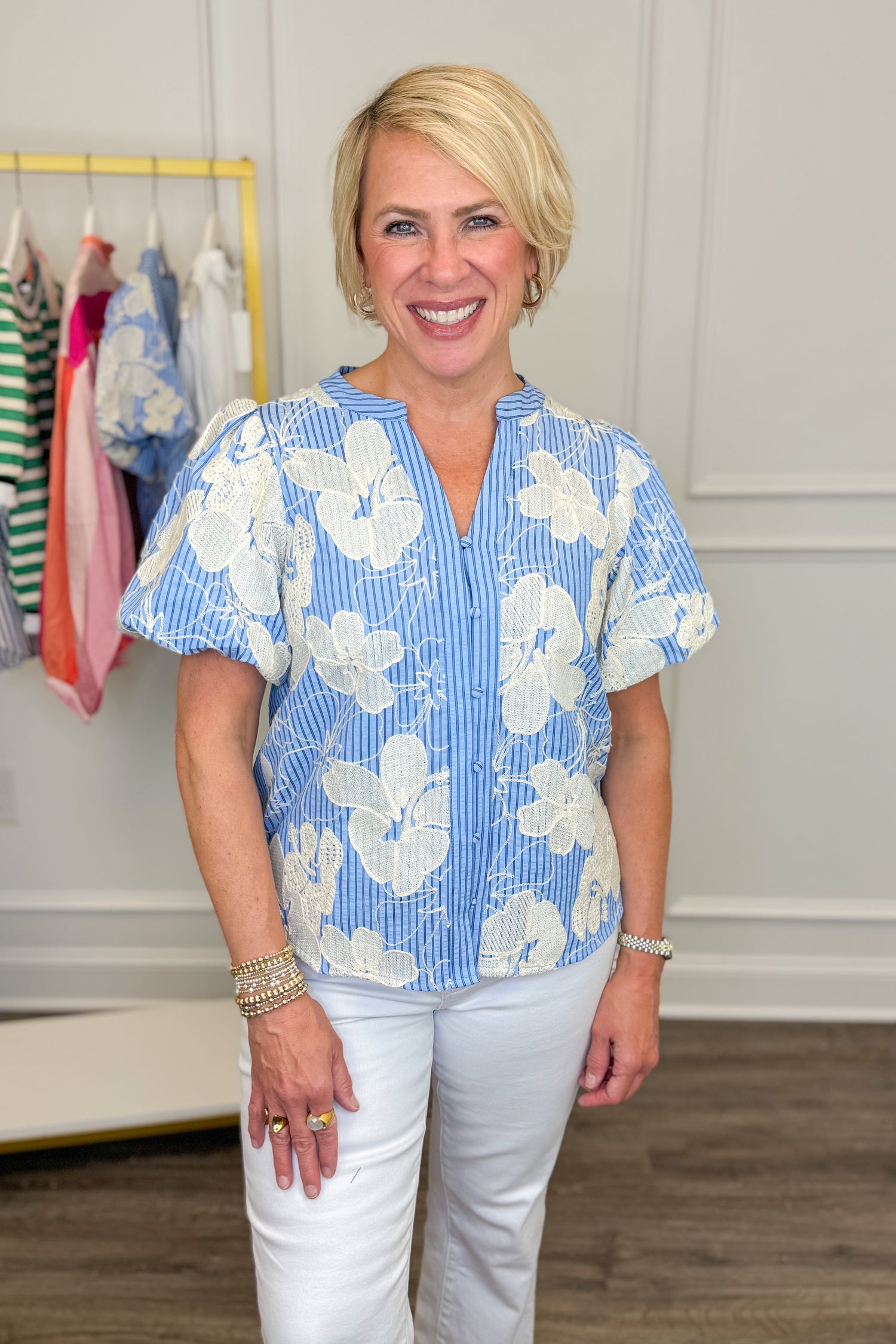 Woman wearing a blue floral blouse in a clothing store.