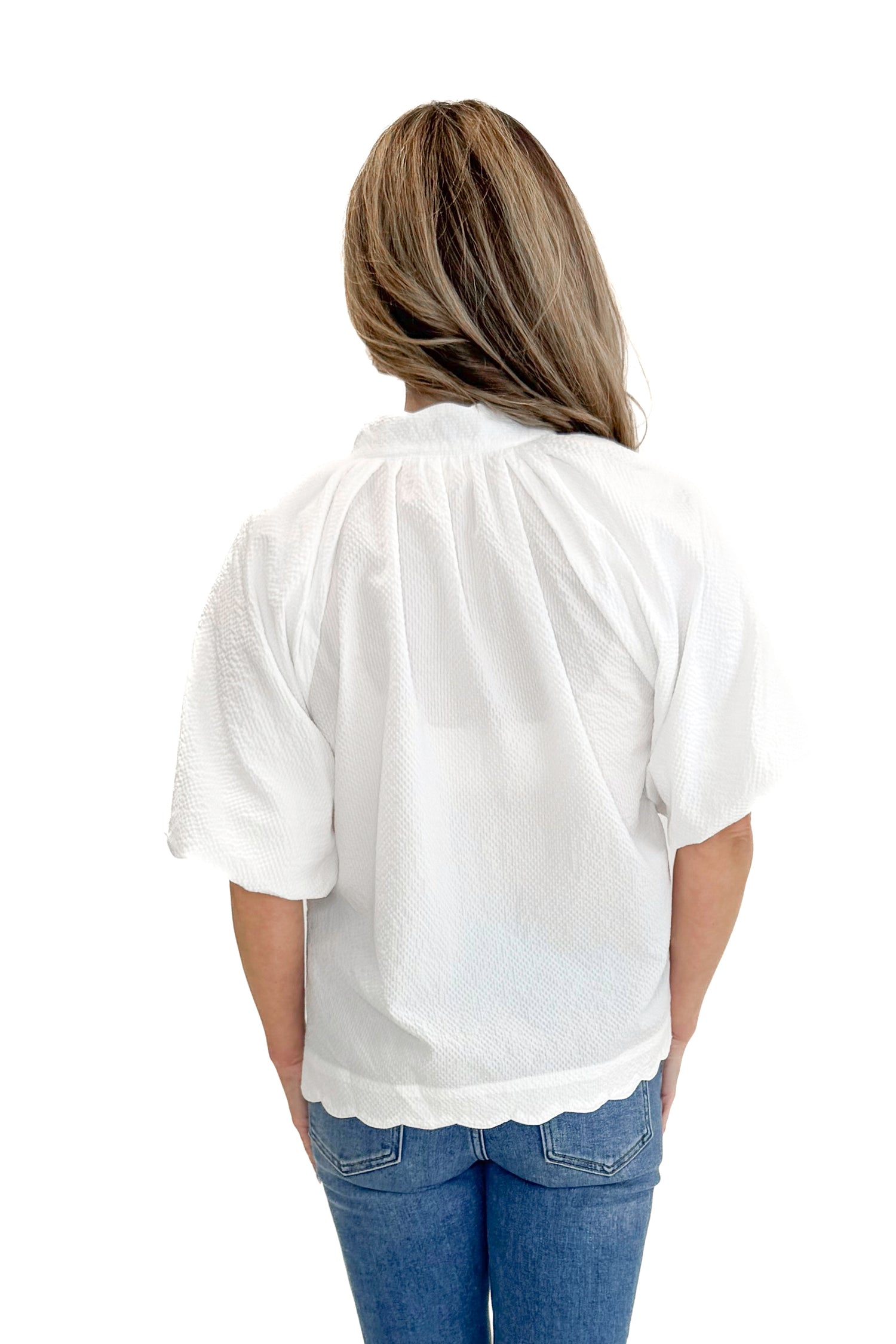 Back view of woman wearing White Scallop Detail V-neck Top with jeans against white studio background.