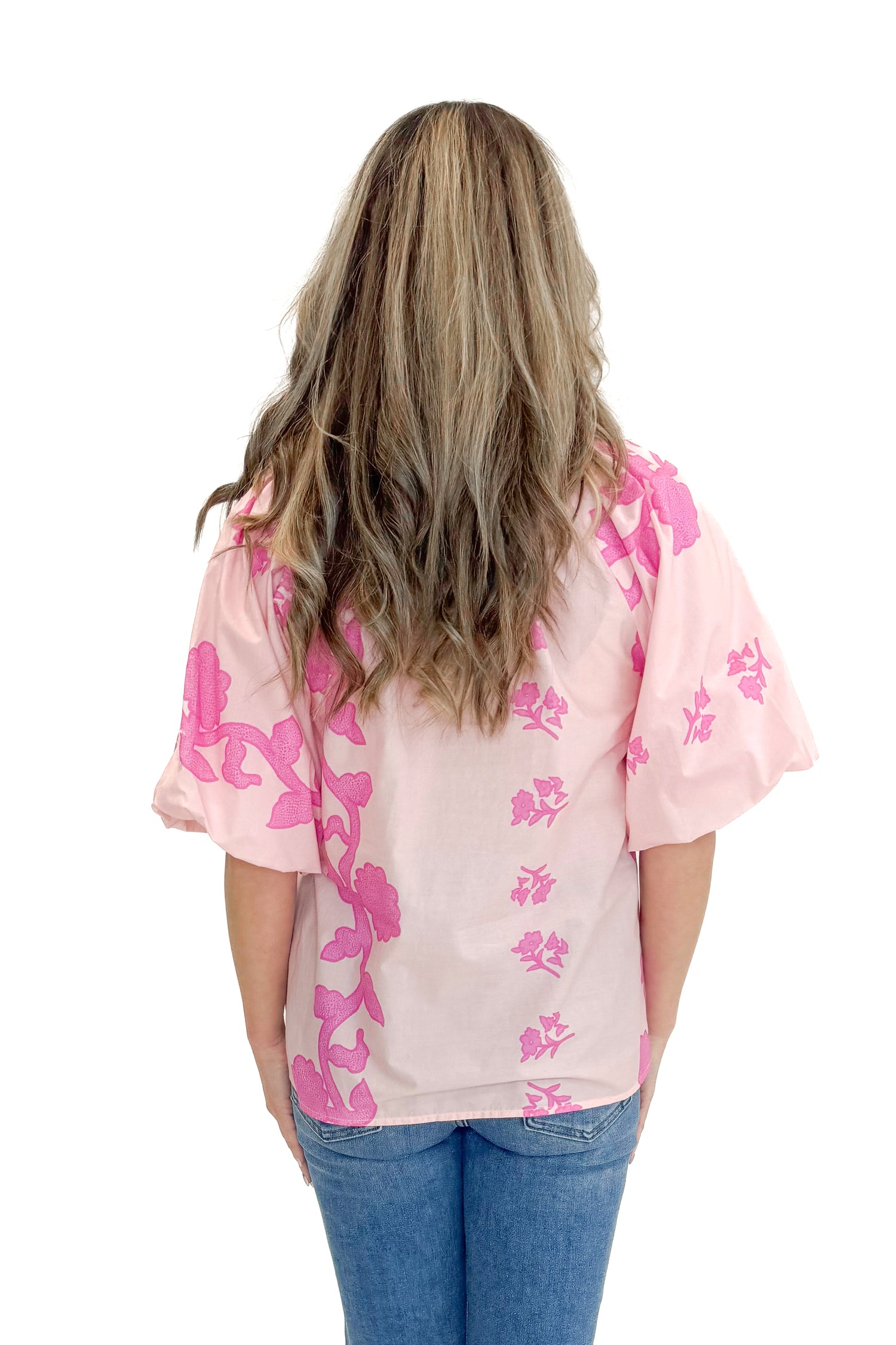 Back view of woman wearing Pink Floral Lace Print Top with jeans against white studio background.
