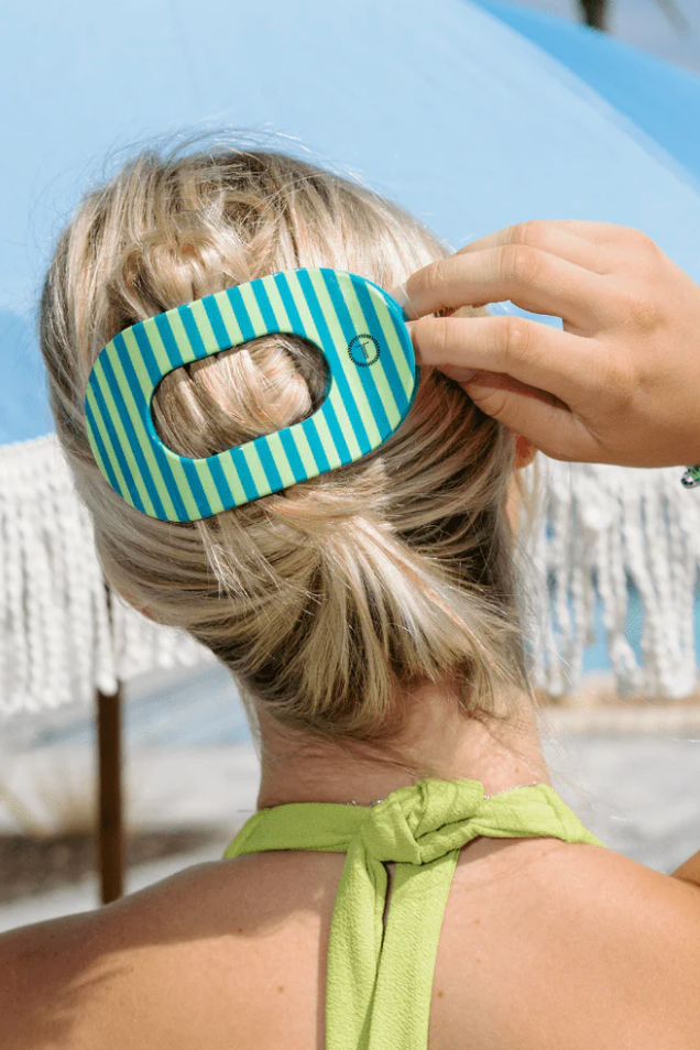 Person wearing a blue striped hair accessory with a blurred beach background