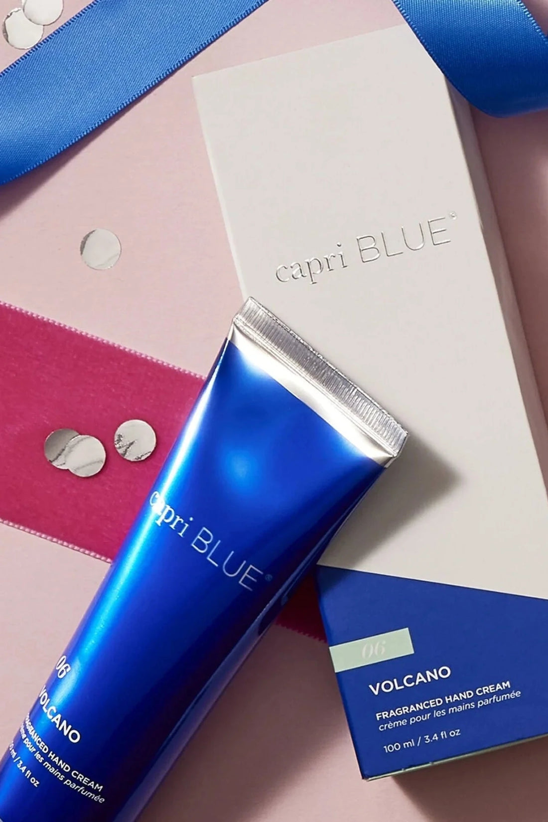Capri Blue Volcano fragranced hand cream on a pink background with decorative ribbons and buttons.