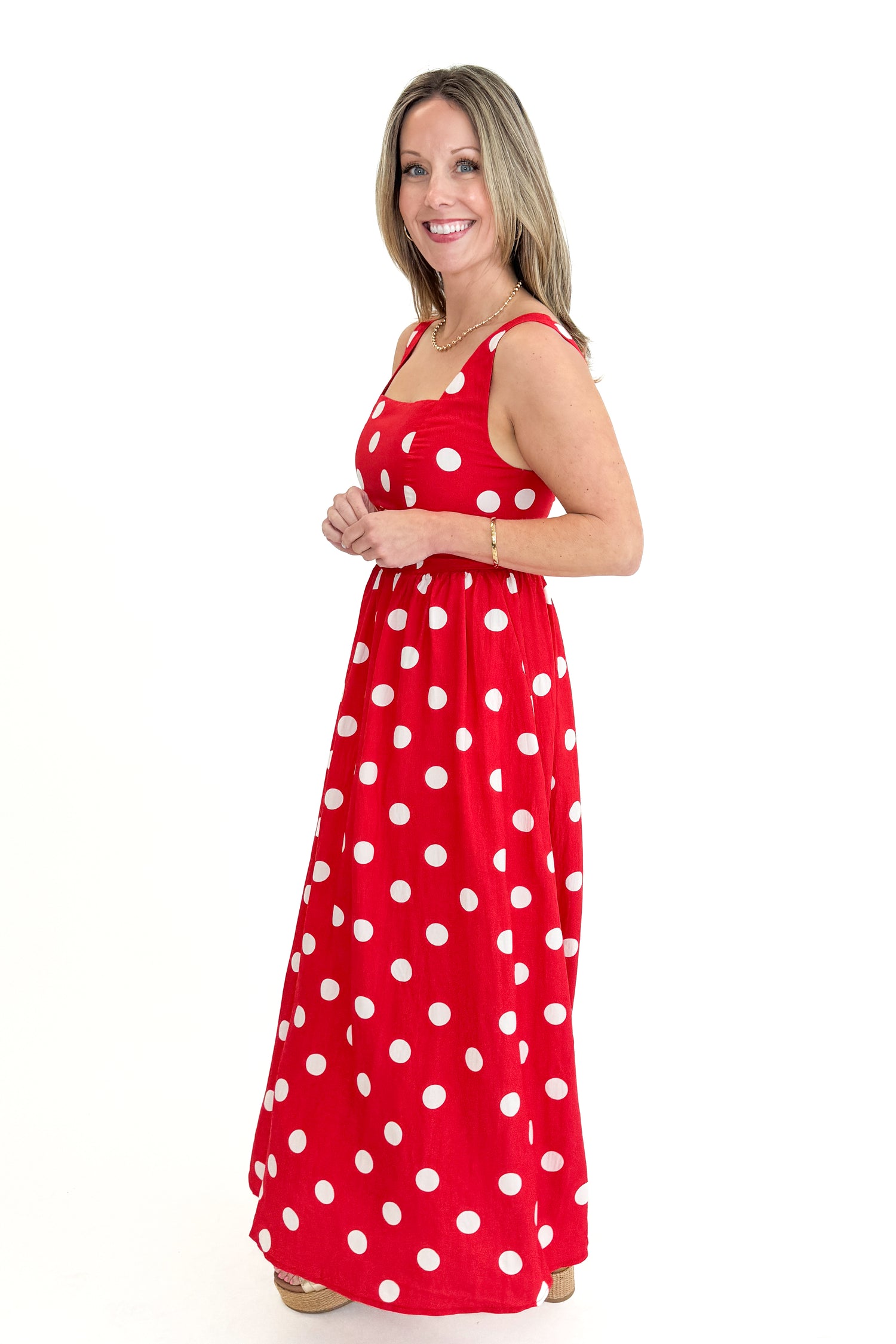 Side view of woman wearing Red &amp; White Polka Dot Midi Dress against white studio background.
