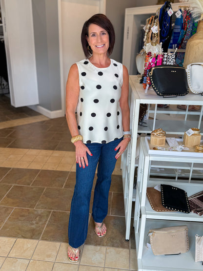 Front view of woman wearing Swagger Boutique’s Cream &amp; Black Polka Dot Satin Tank with jeans standing at the store.