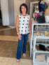 Front view of woman wearing Swagger Boutique’s Cream & Black Polka Dot Satin Tank with jeans standing at the store.