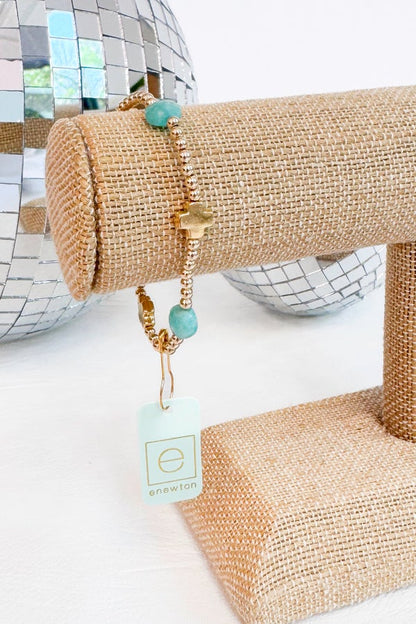Gold bracelet with turquoise beads on a textured surface with disco ball background