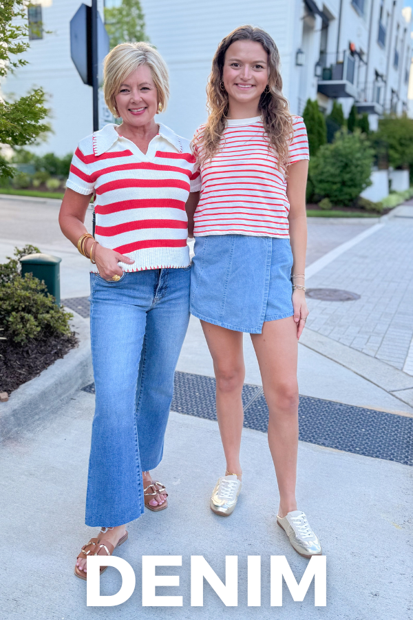 Two women wearing matching red and white striped shirts and blue denim jeans standing on a sidewalk.