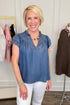 Woman wearing a blue top and white pants in a clothing store setting
