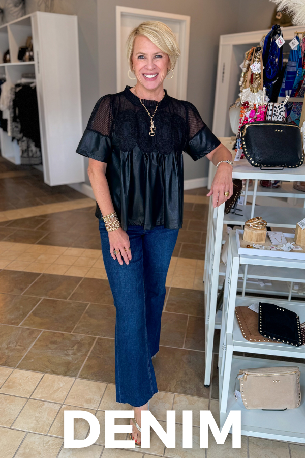 A smiling blonde woman stands in a boutique wearing a black sheer-sleeve peplum top and dark blue denim flare pants. The word 'DENIM' is printed in large white letters at the bottom of the image.