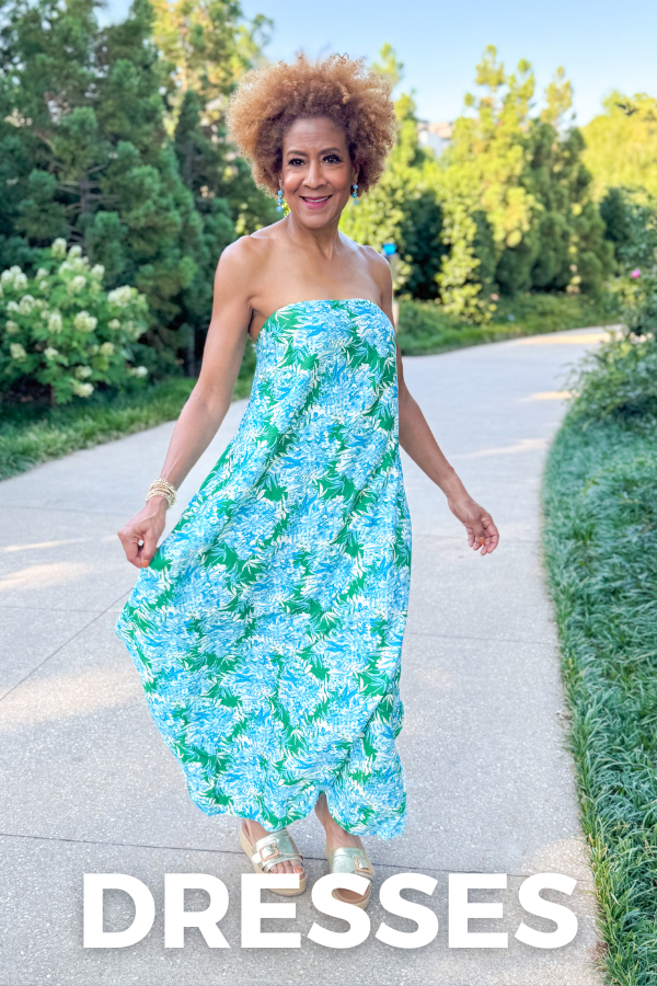 Woman in a strapless floral dress walking outdoors with trees and grass in the background.