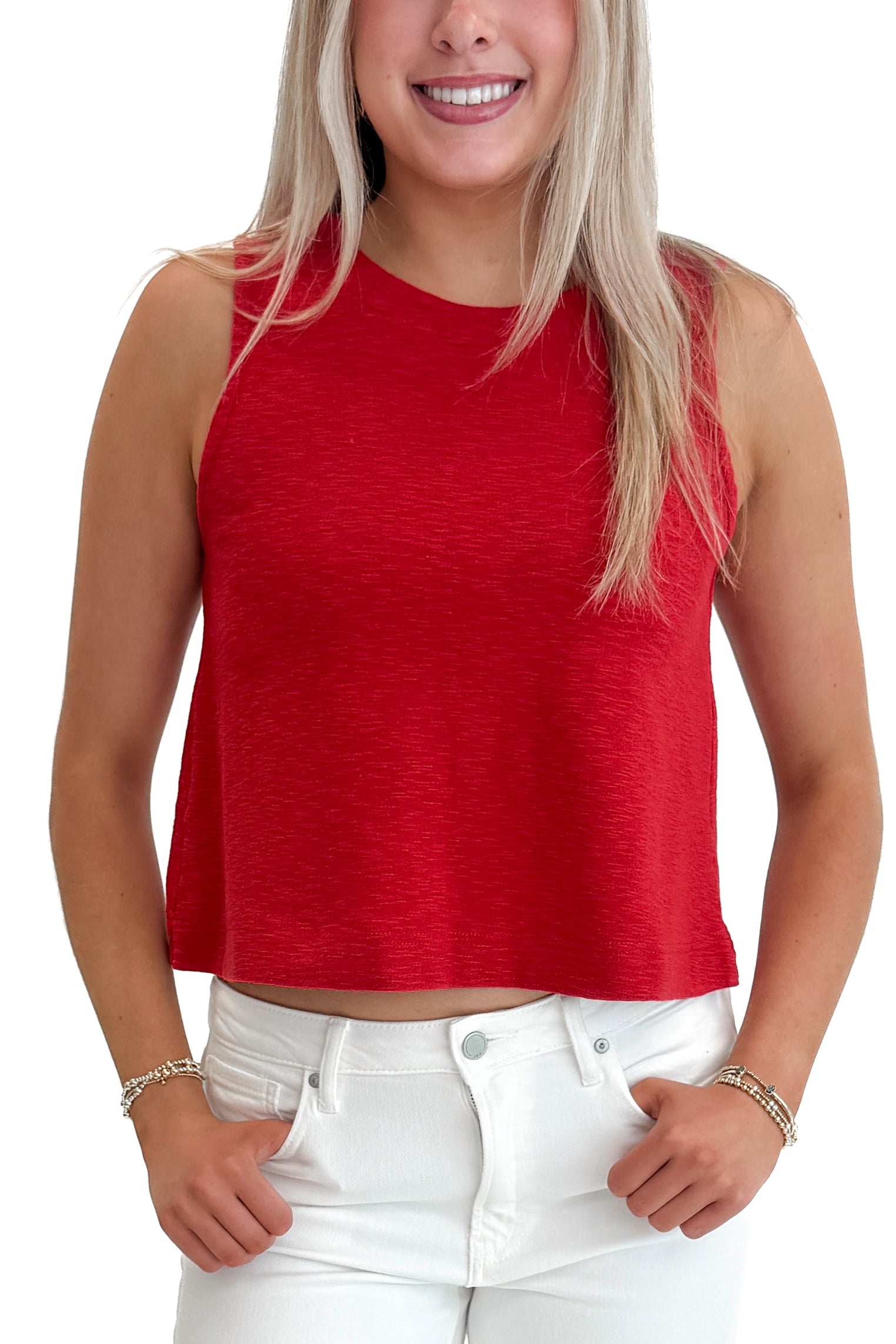 Front detail view of woman wearing Red Boxy Tank Top with white jeans against white studio background.