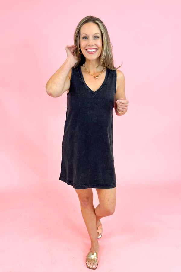 Woman wearing a black sleeveless dress against a pink background