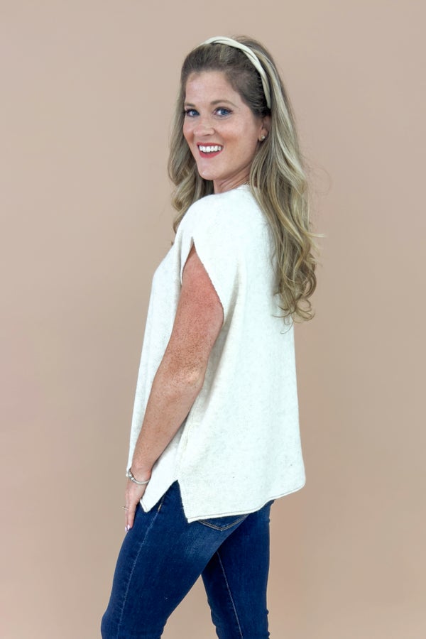 Woman wearing a white blouse and blue jeans against a beige background
