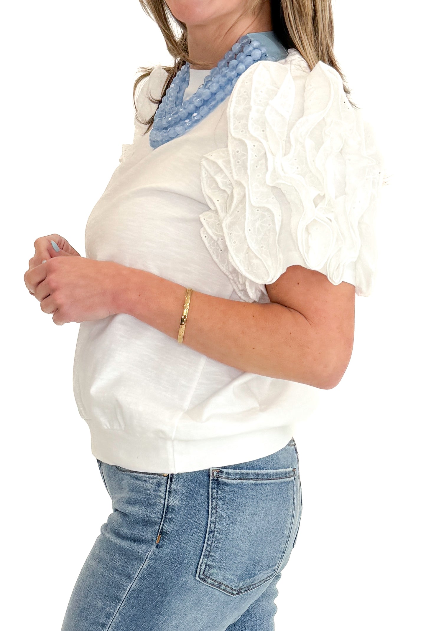 Side detail view of woman wearing White Ruffle Sleeve Detail Top by Fate with jeans against white studio background.