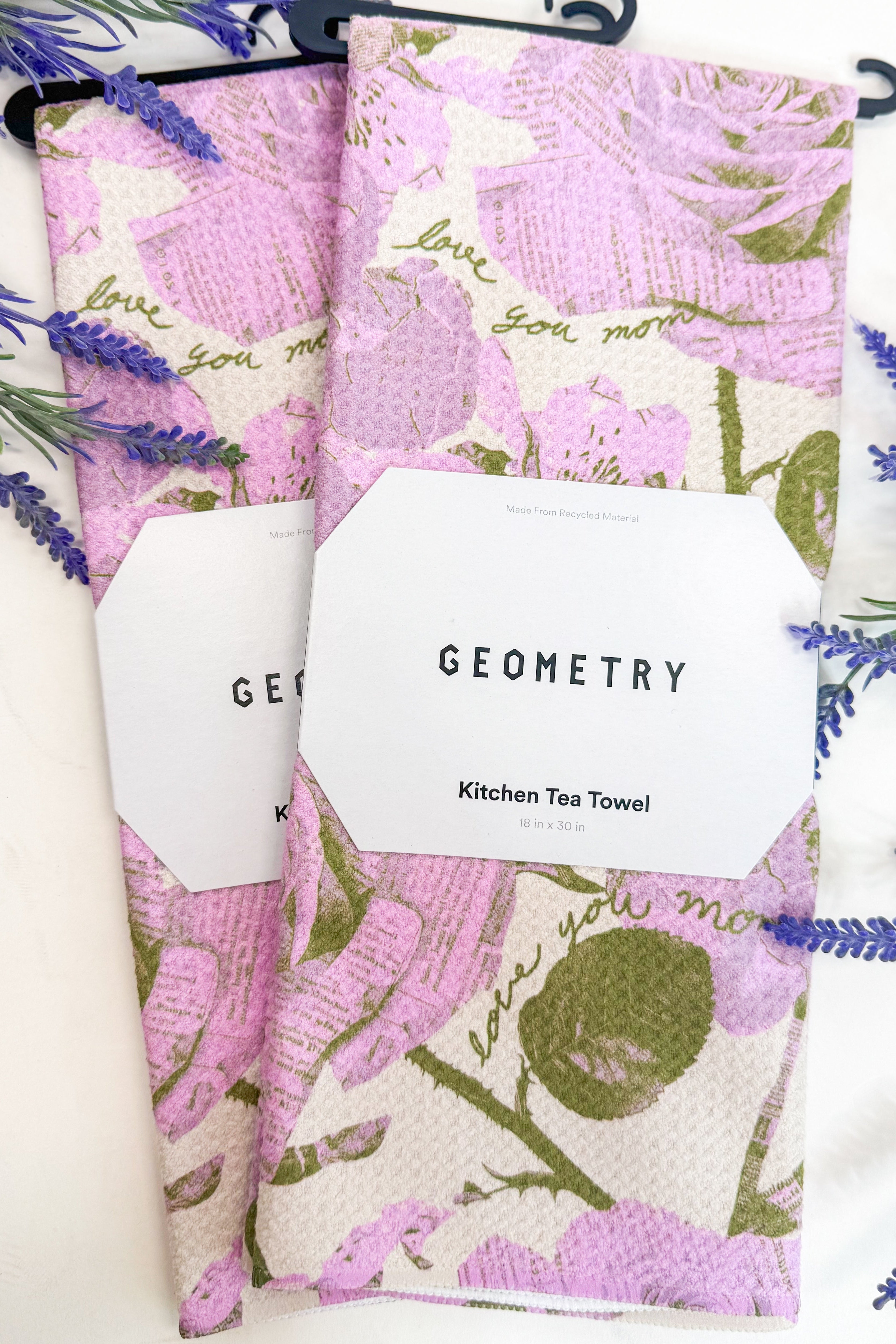 Floral patterned towels with purple flowers and green leaves on a light background 