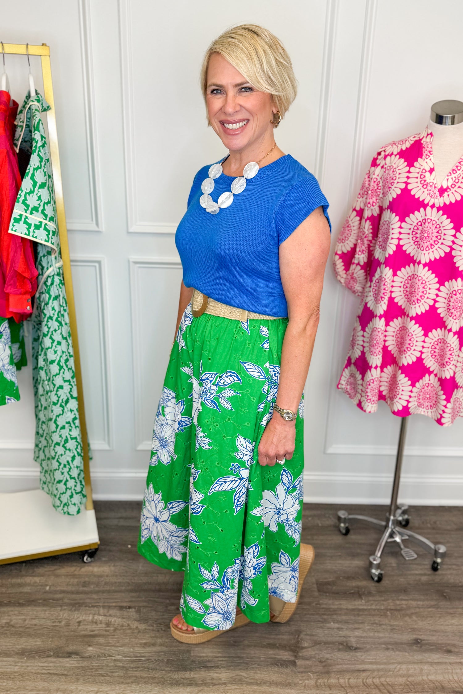 woman wearing green eyelet detailing skirt with white and blue printed flowers paired with a blue top and necklace