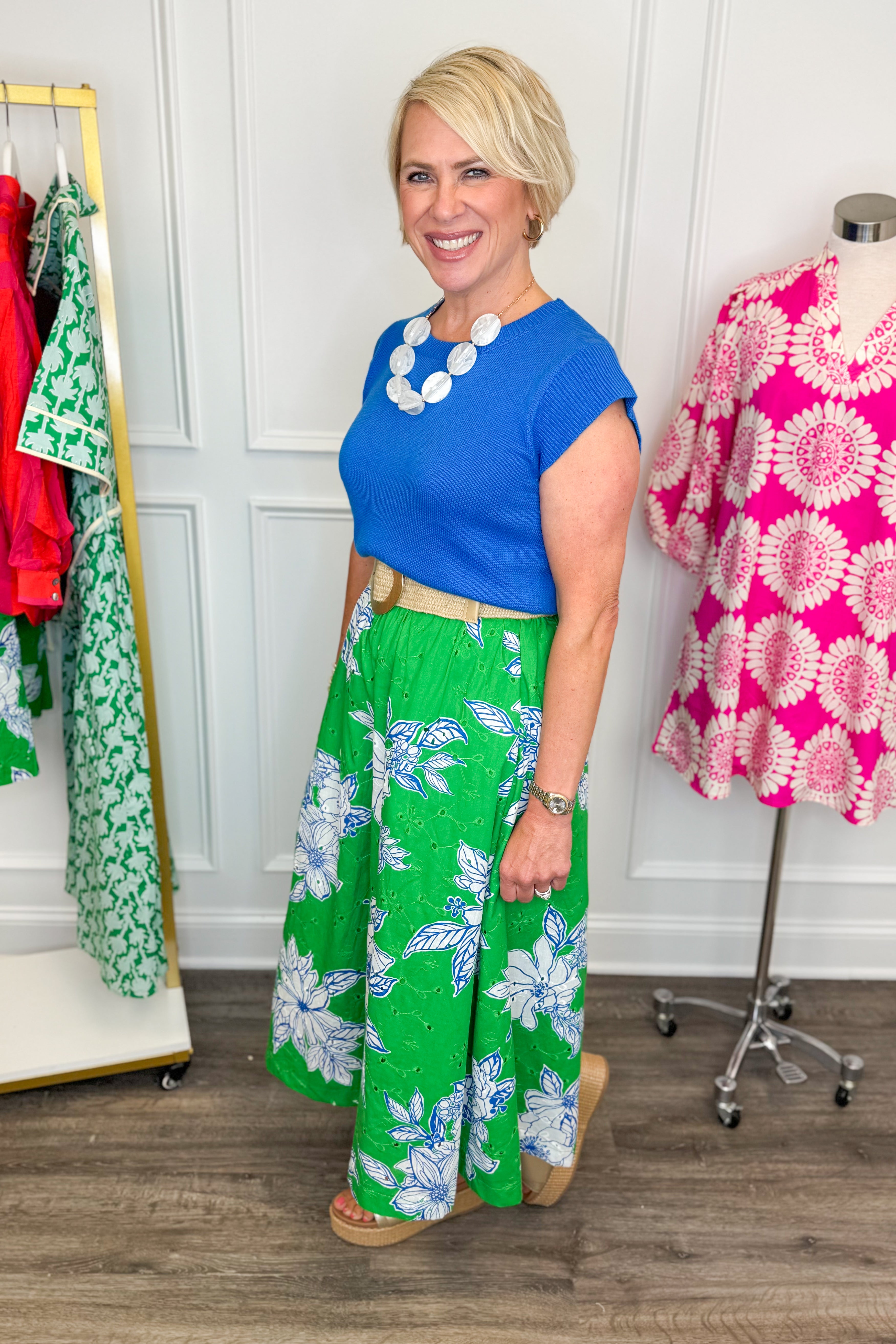 woman wearing green eyelet detailing skirt with white and blue printed flowers paired with a blue top and necklace