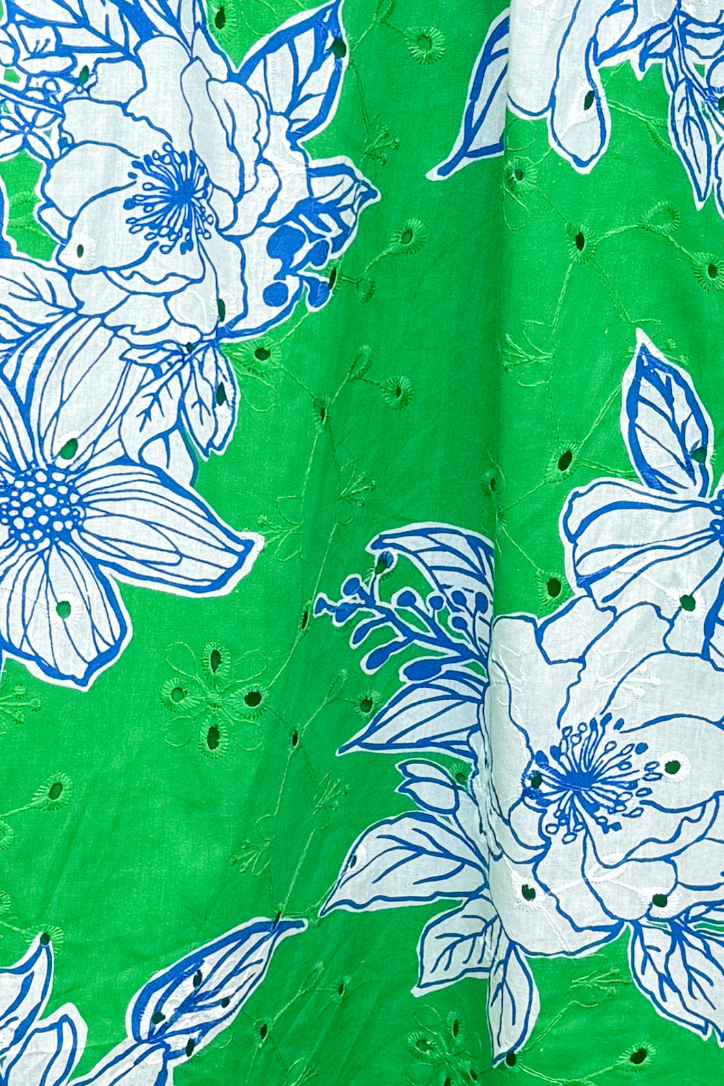detail shot of green eyelet detailing skirt with white and blue printed flowers