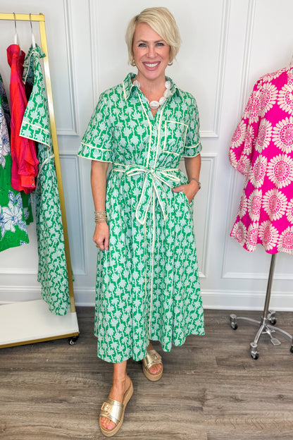 woman wearing green printed button down midi dress with tie detailing on a white background