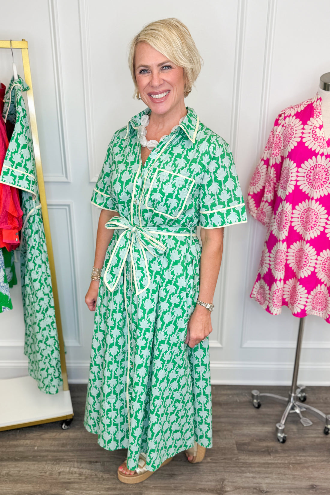woman wearing green printed button down midi dress with tie detailing on a white background