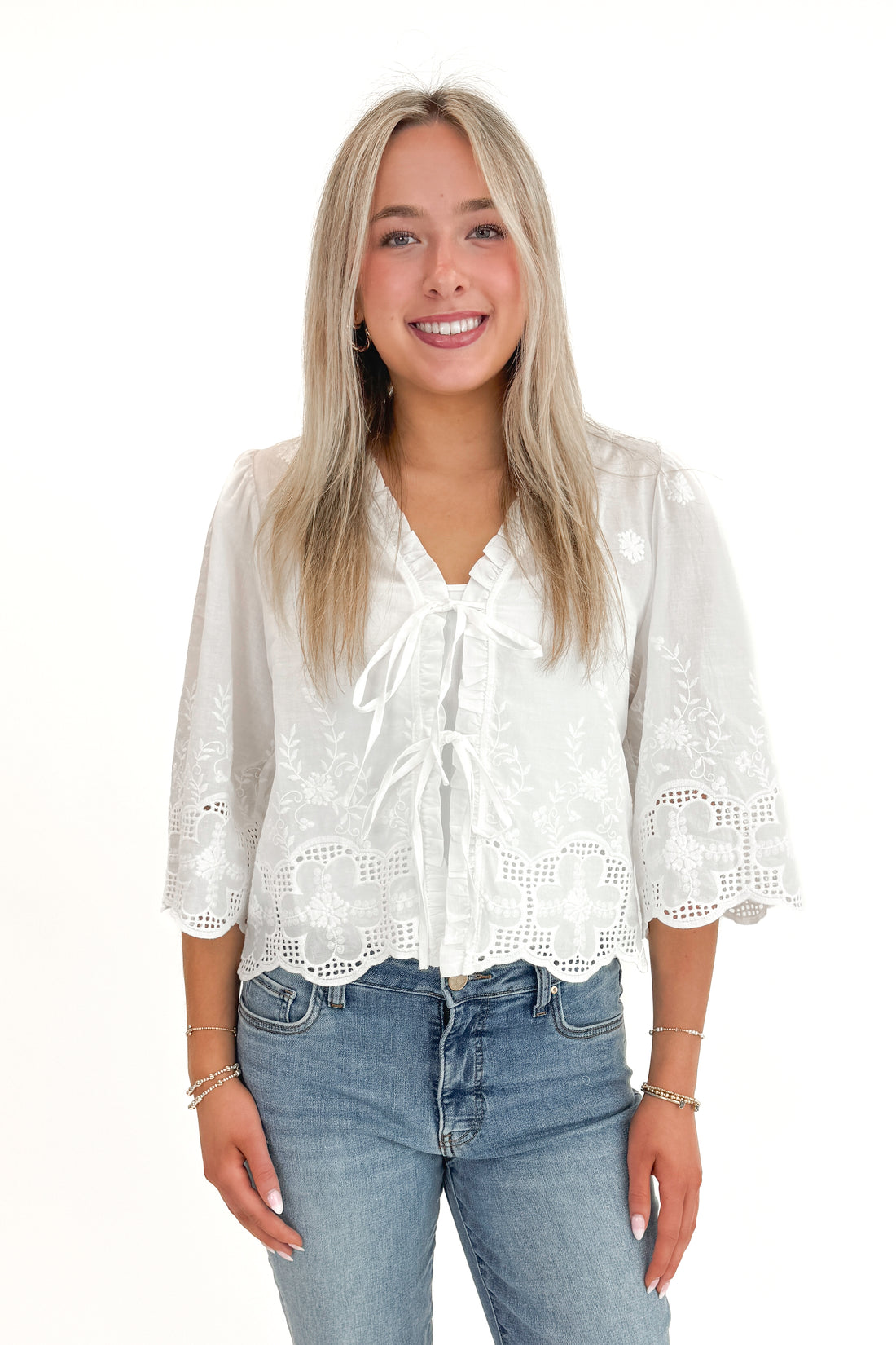 Front view of woman wearing White Embroidered Tie Detail Top with jeans against white studio background.