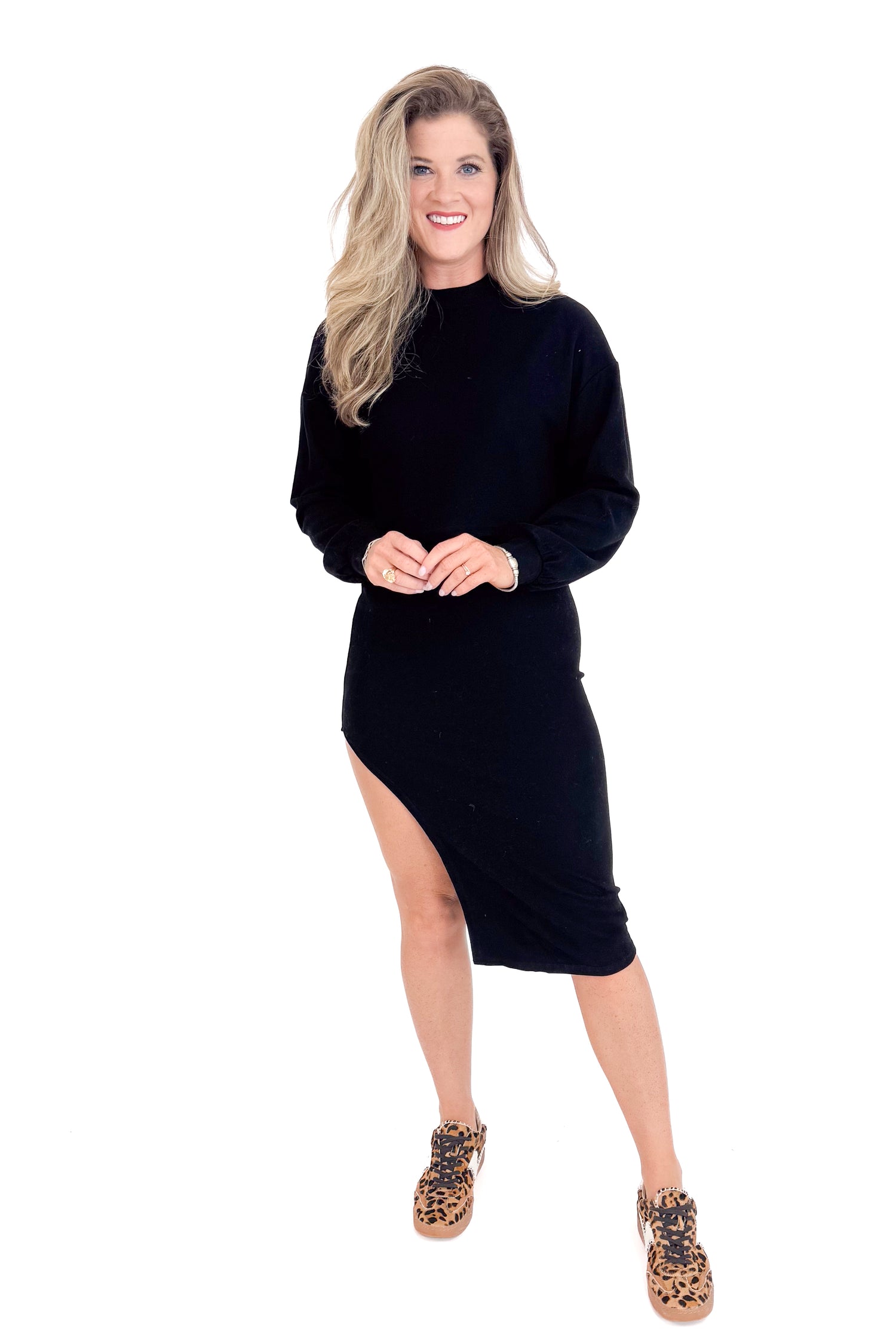 Woman wearing a black dress with a slit on a white background