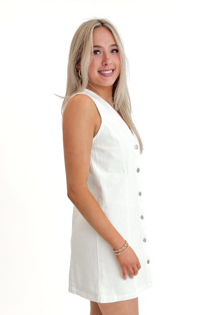 Side view of woman wearing White Denim Button Up Dress against white studio background.