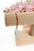 Bracelet on a burlap stand with pink flowers in the background