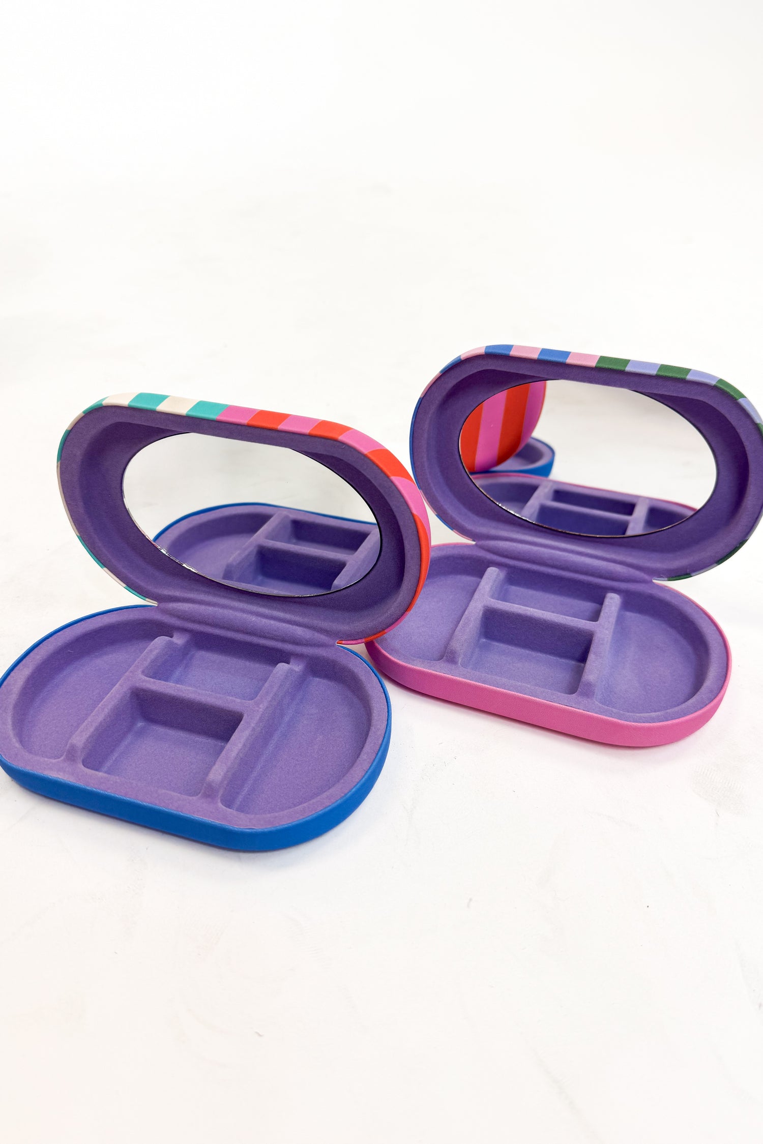 Two open purple jewelry organizers with colorful accents on a white background