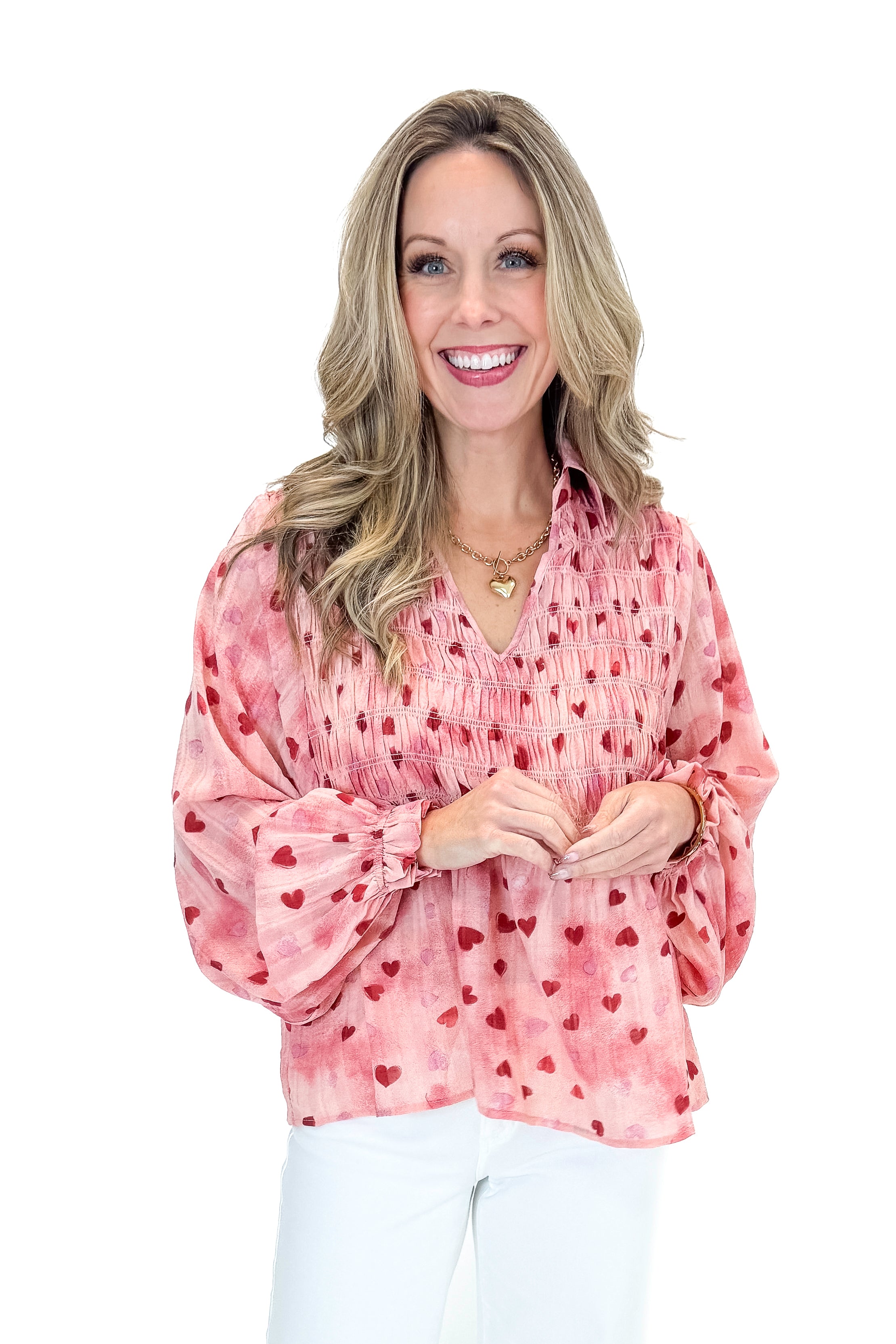 Front view of woman wearing Pink Heart Printed Smocked Detail Top with jeans against white studio background.
