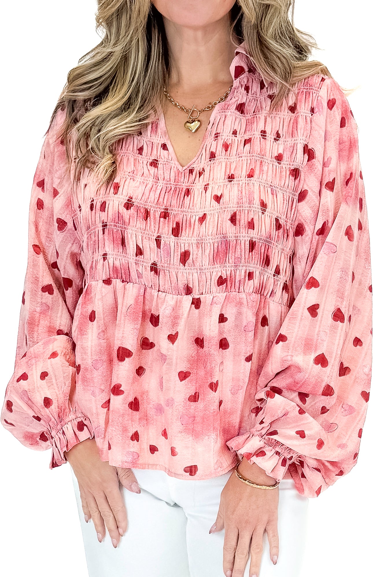 Front detail view of woman wearing Pink Heart Printed Smocked Detail Top with jeans against white studio background.