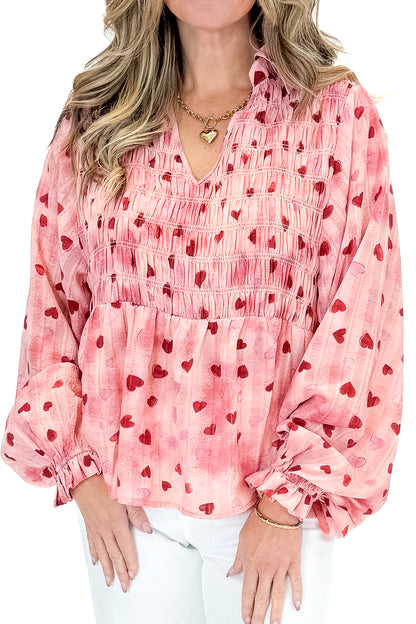 Front detail view of woman wearing Pink Heart Printed Smocked Detail Top with jeans against white studio background.